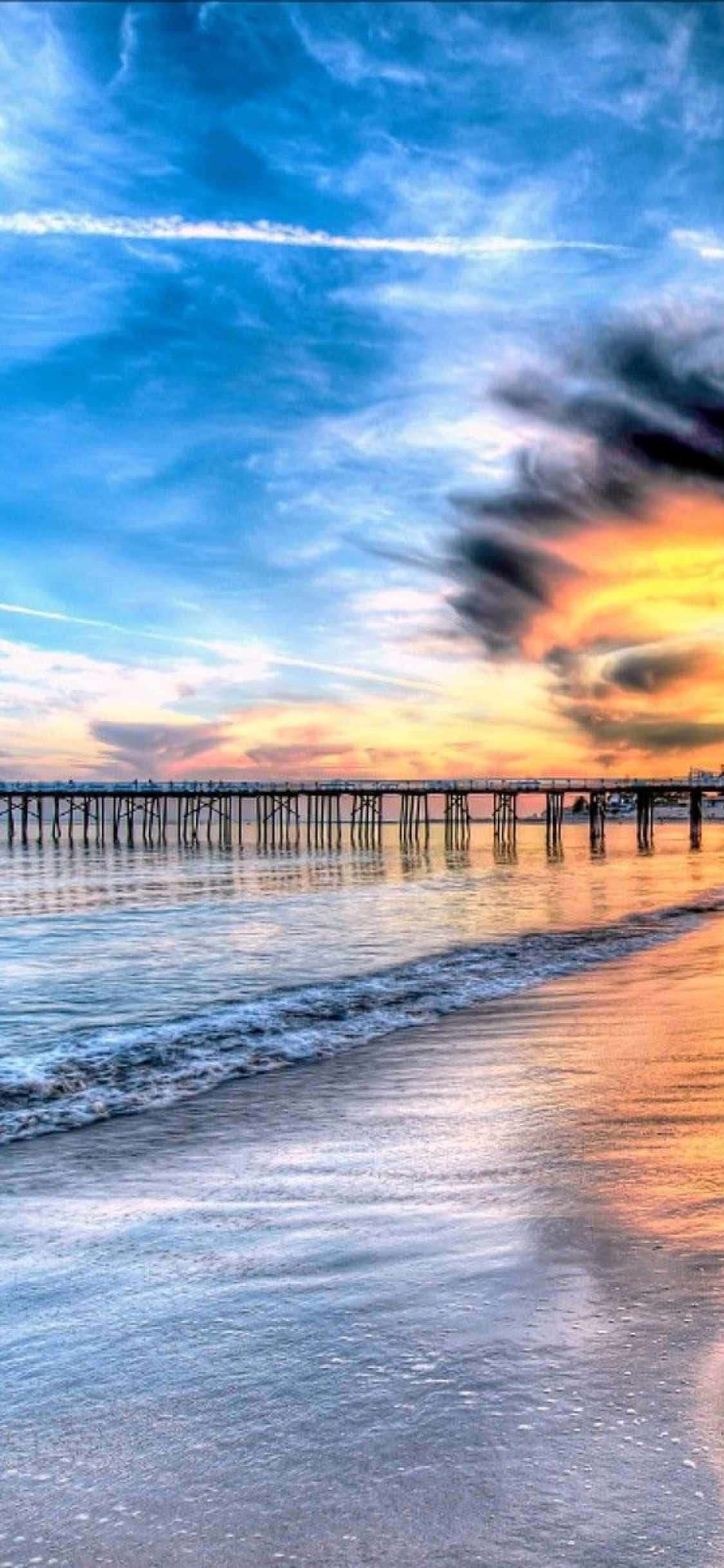 a pier with a sunset over the ocean वॉलपेपर