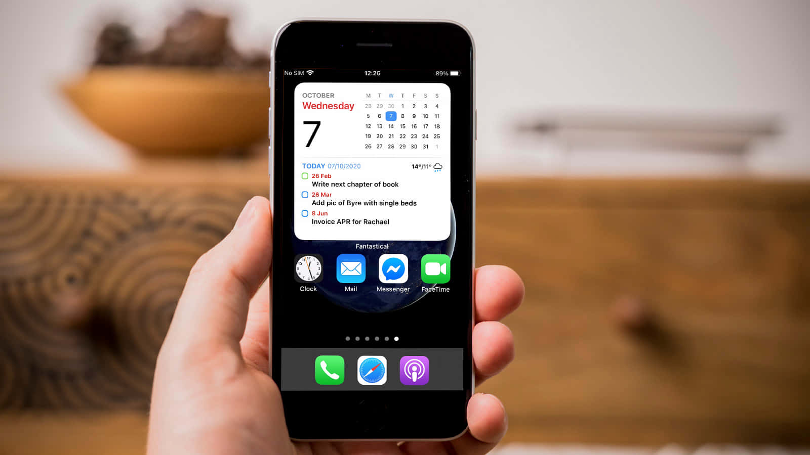 एक व्यक्ति जिसके हाथ में iPhone है जिस पर कैलेंडर दिख रहा है वॉलपेपर