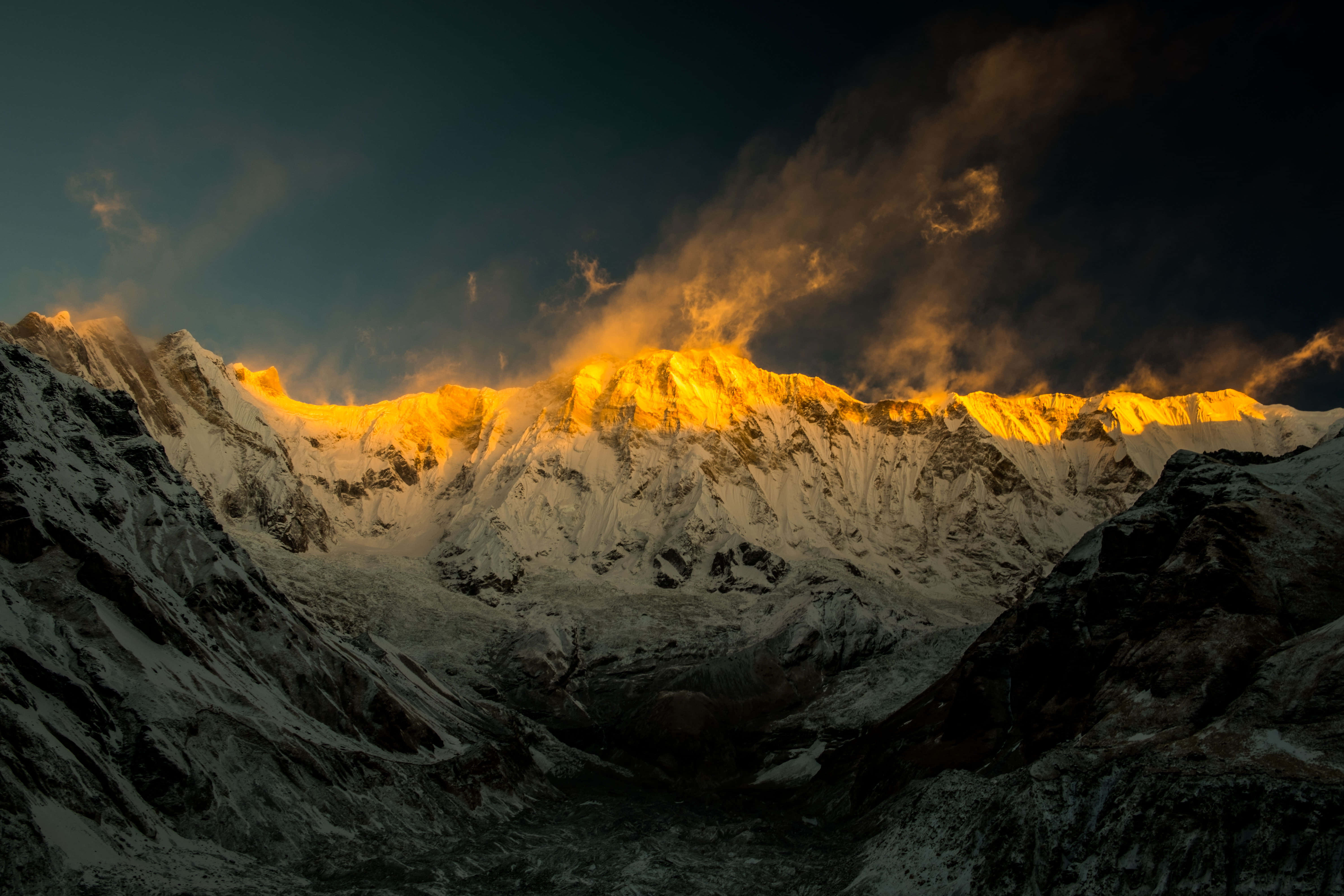 एक पर्वत श्रृंखला जिस पर सुनहरी रोशनी चमक रही है वॉलपेपर