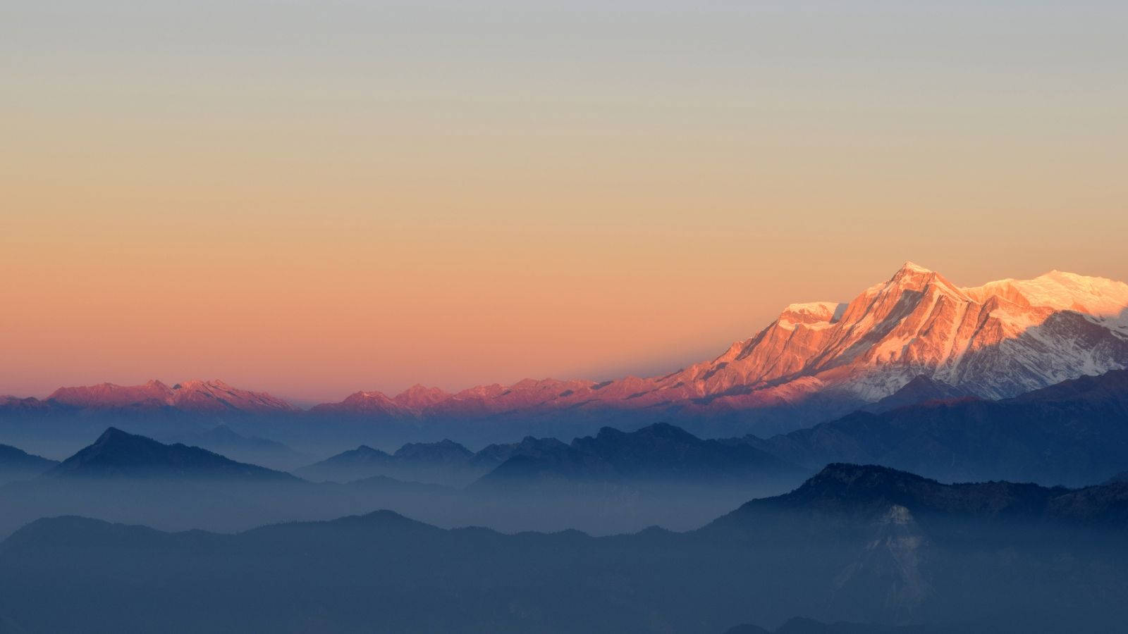 लुभावने सूर्यास्त के दौरान बर्फ से ढके पहाड़ों का दृश्य वॉलपेपर