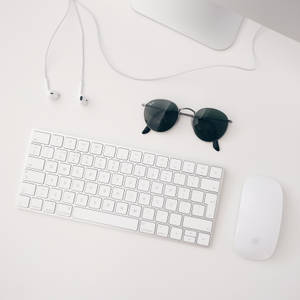 सफेद Apple MAC सेट-अप का मिनिमलिस्ट वॉलपेपर जिसमें iMAC, वायरलेस कीबोर्ड, मैजिक माउस और ईयरफोन शामिल हैं