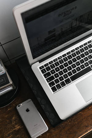 सिल्वर MacBook के साथ iPhone डेस्क — 小米 Pad 7 Ultra वॉलपेपर